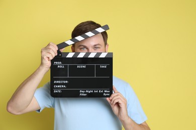 Making movie. Man with clapperboard on yellow background