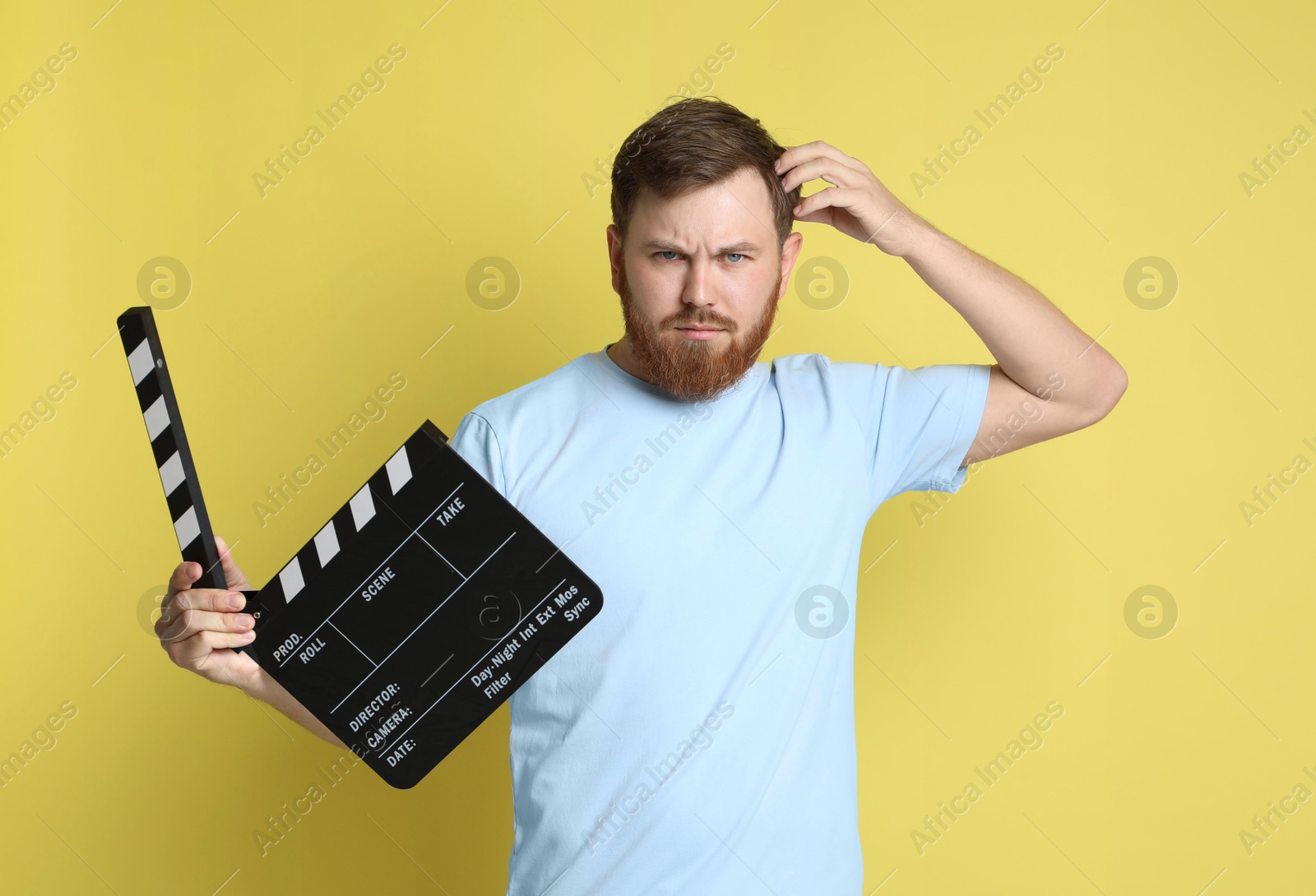Photo of Making movie. Thoughtful man with clapperboard on yellow background