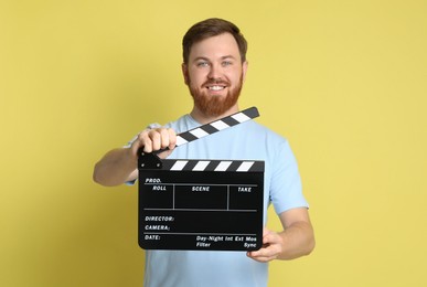 Making movie. Smiling man with clapperboard on yellow background