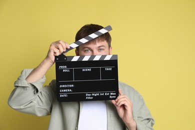 Making movie. Man with clapperboard on yellow background