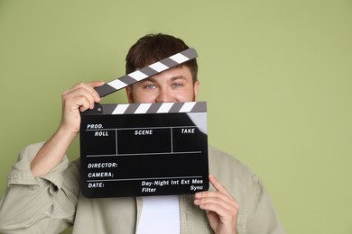 Photo of Making movie. Man with clapperboard on green background