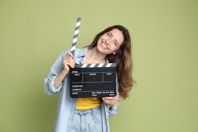 Making movie. Smiling woman with clapperboard on green background