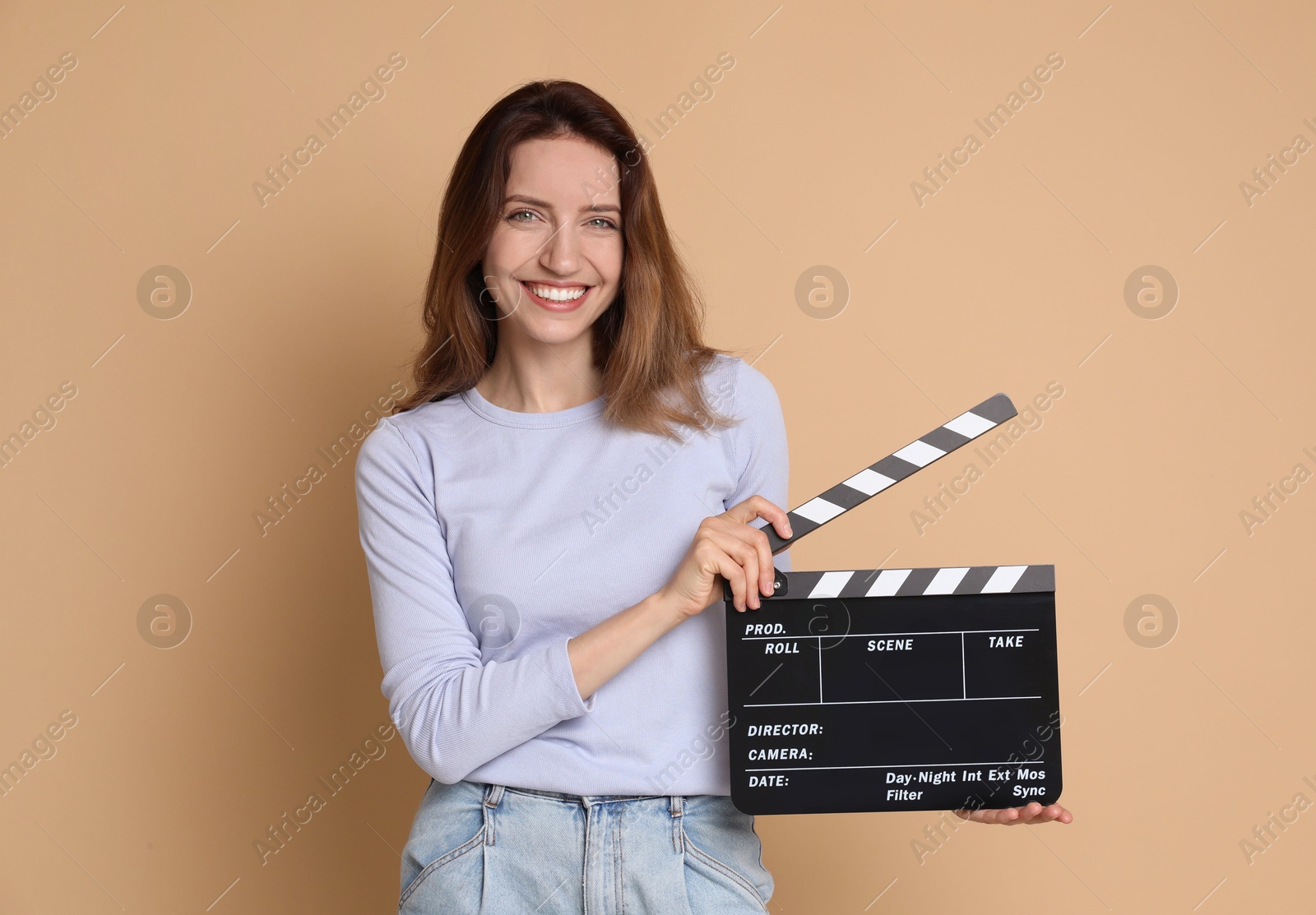 Photo of Making movie. Smiling woman with clapperboard on beige background