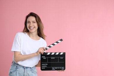 Making movie. Smiling woman with clapperboard on pink background. Space for text