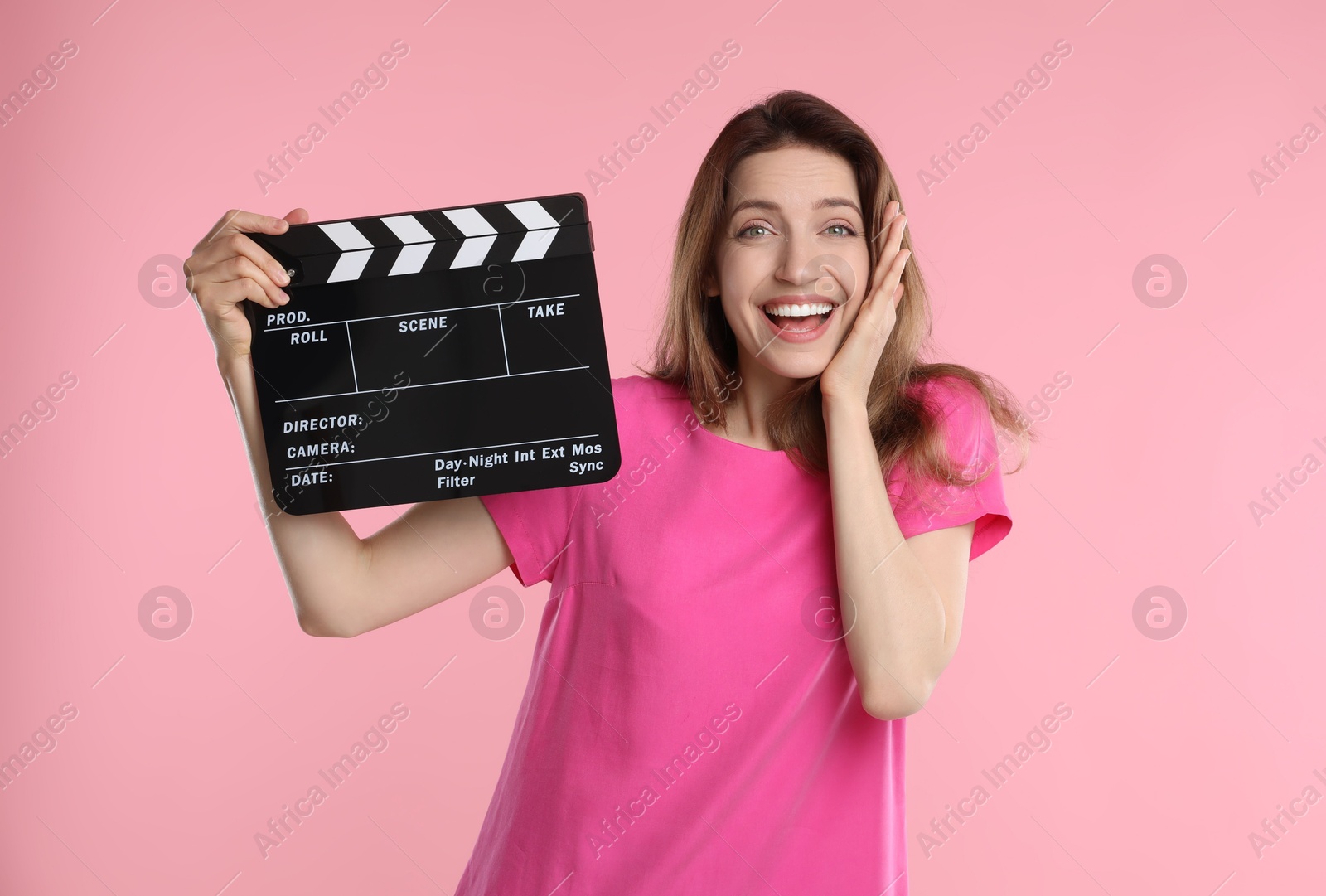 Photo of Making movie. Smiling excited woman with clapperboard on pink background