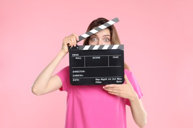 Making movie. Woman with clapperboard on pink background