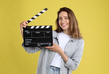 Making movie. Smiling woman with clapperboard on yellow background
