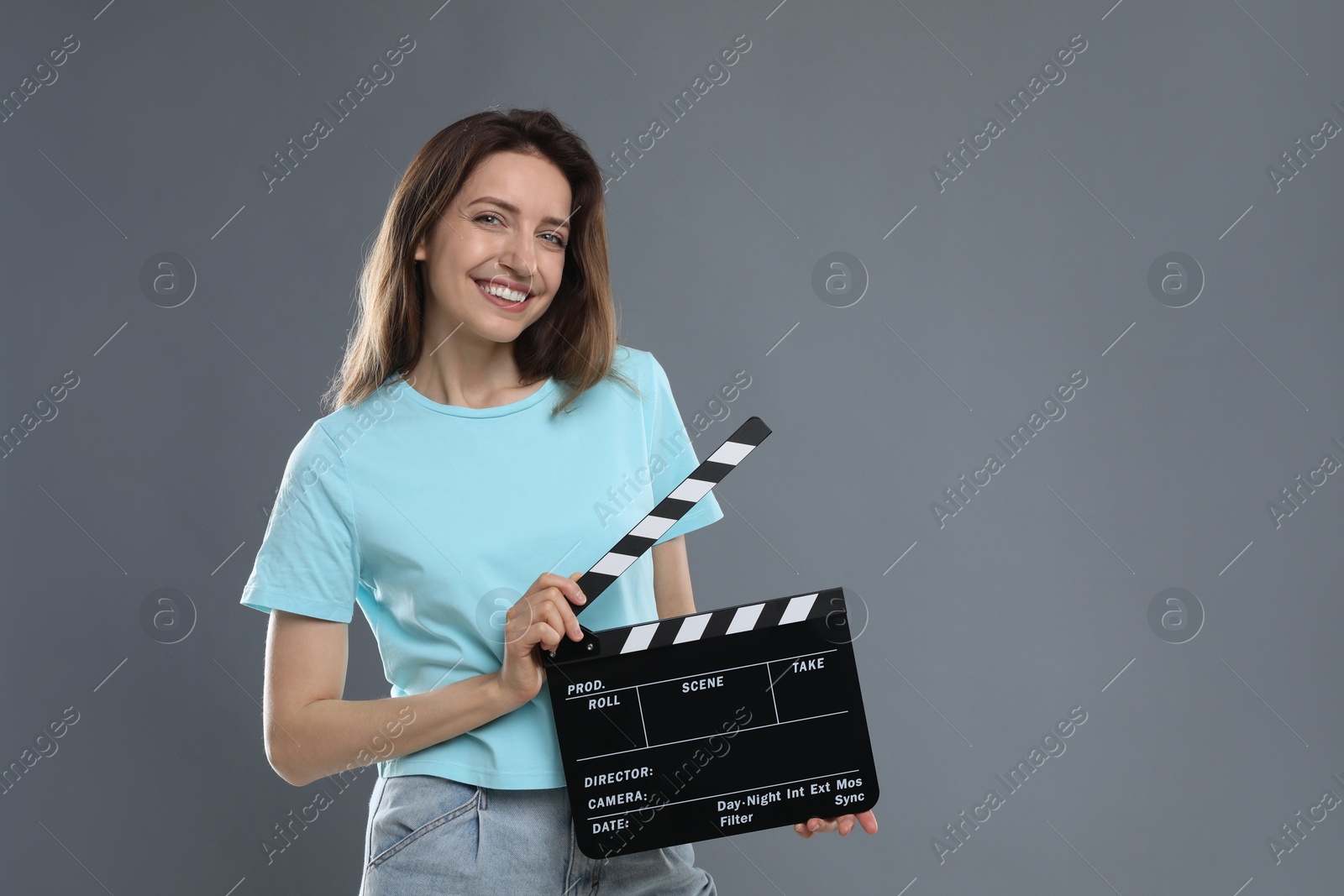 Photo of Making movie. Smiling woman with clapperboard on grey background. Space for text