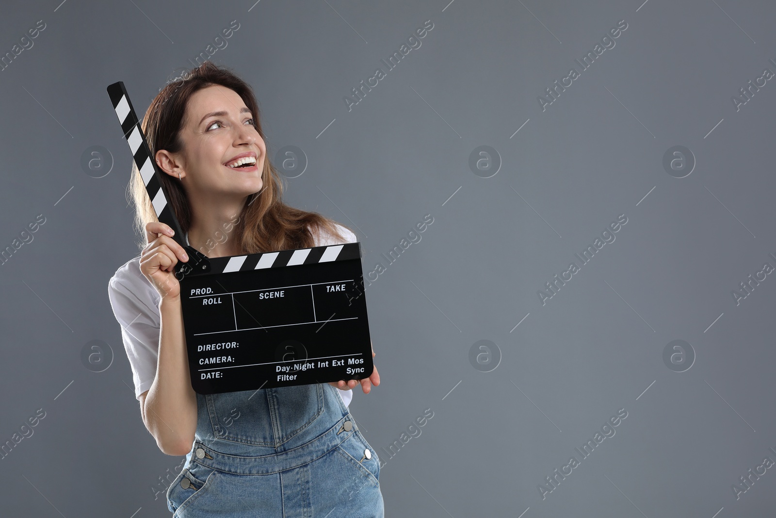 Photo of Making movie. Smiling woman with clapperboard on grey background. Space for text