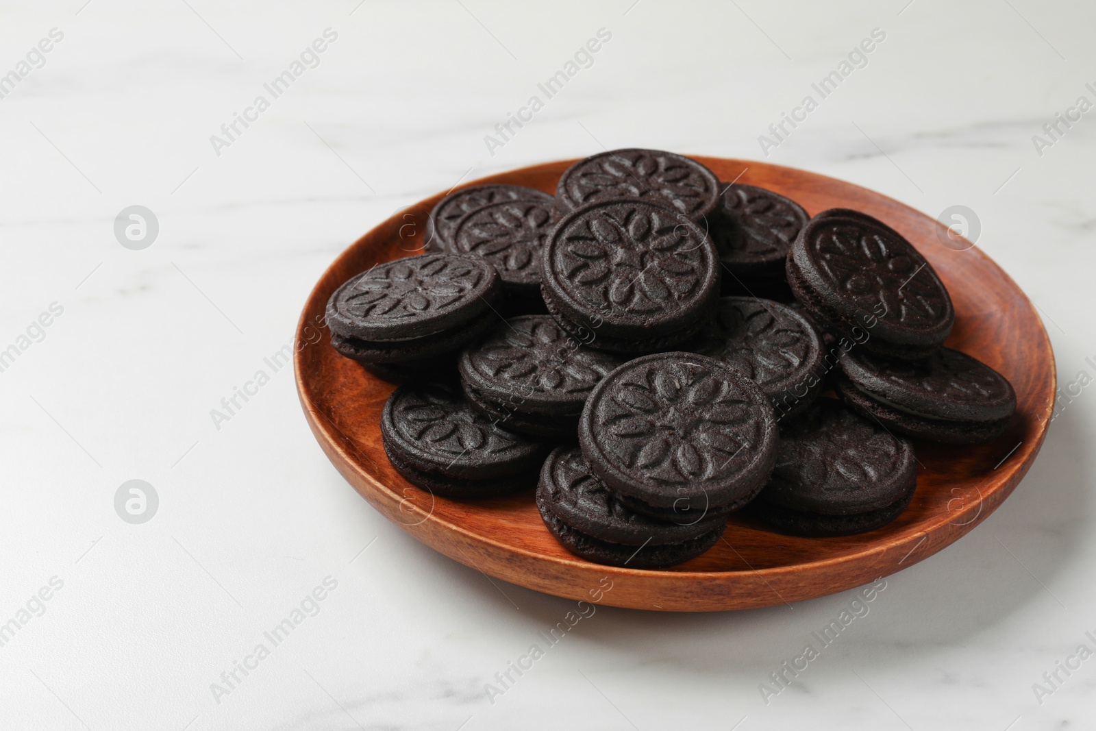 Photo of Plate with tasty sandwich cookies on white marble table, closeup. Space for text