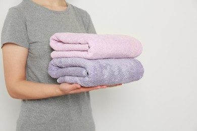 Photo of Woman holding folded soft terry towels on white background, closeup. Space for text