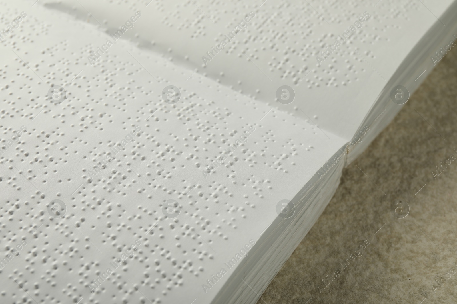 Photo of Book with Braille text on beige textured table, closeup. Education and leisure for blind people