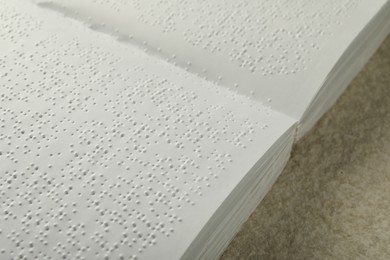 Book with Braille text on beige textured table, closeup. Education and leisure for blind people