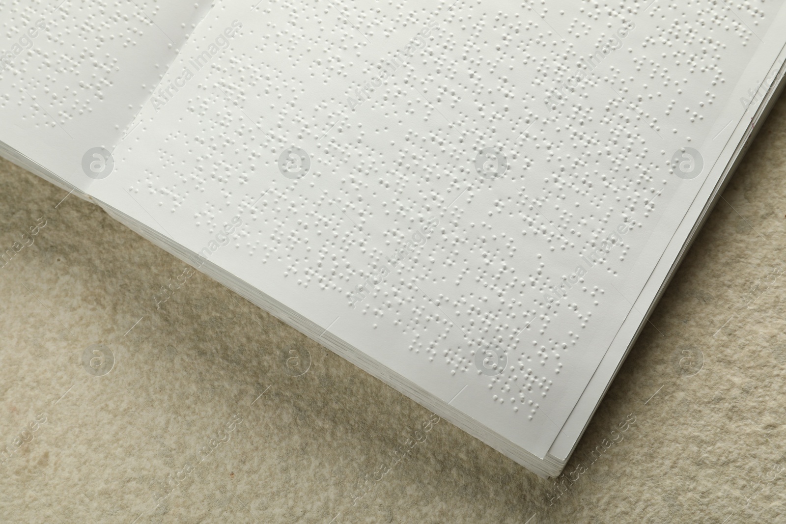 Photo of Book with Braille text on beige textured table, top view. Education and leisure for blind people