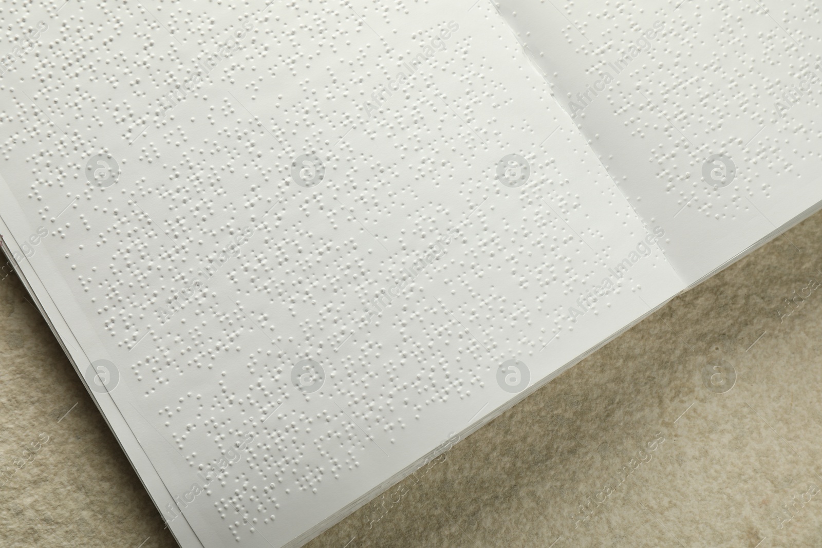 Photo of Book with Braille text on beige textured table, top view. Education and leisure for blind people