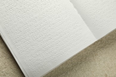 Book with Braille text on beige textured table, top view. Education and leisure for blind people