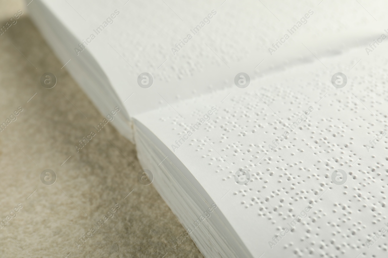 Photo of Book with Braille text on beige textured table, closeup. Education and leisure for blind people