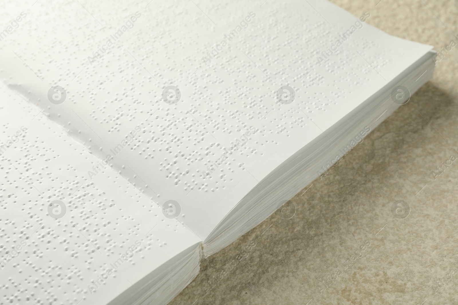 Photo of Book with Braille text on beige textured table, closeup. Education and leisure for blind people