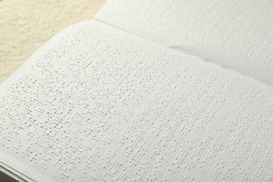 Photo of Book with Braille text on beige table, closeup