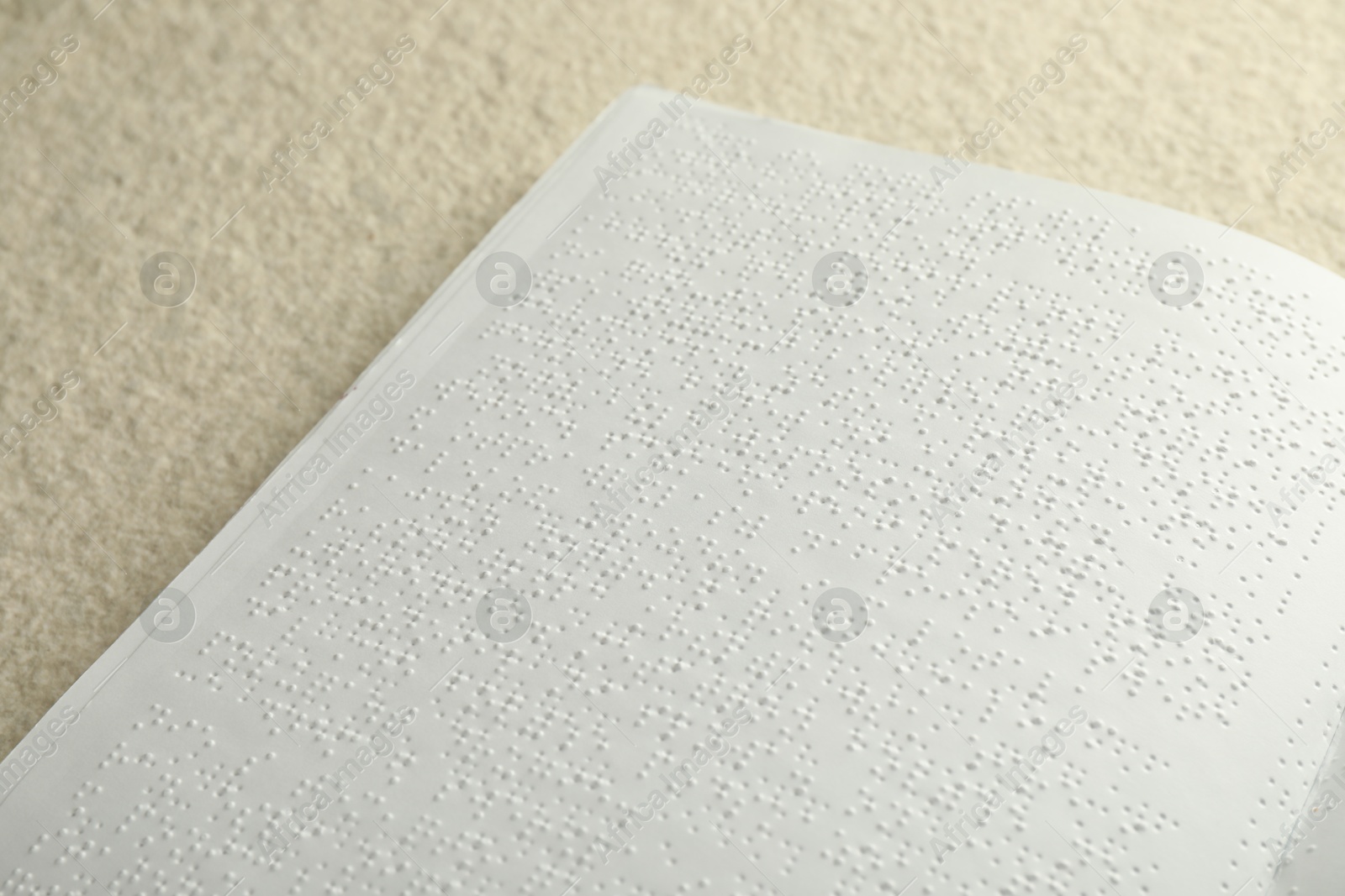 Photo of Book with Braille text on beige textured table, closeup. Education and leisure for blind people