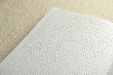 Book with Braille text on beige textured table, closeup. Education and leisure for blind people