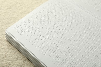 Photo of Book with Braille text on beige textured table, closeup. Education and leisure for blind people