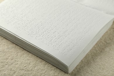 Photo of Book with Braille text on beige textured table, closeup. Education and leisure for blind people