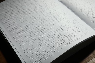 Photo of Book with Braille text on table, closeup. Education and leisure for blind people