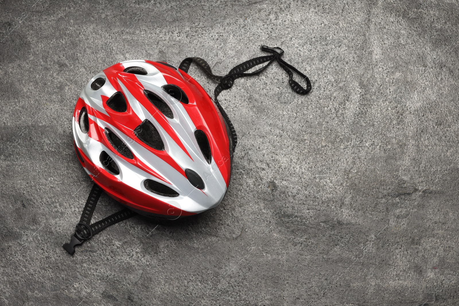 Photo of Modern protective helmet on grey stone surface, top view. Space for text