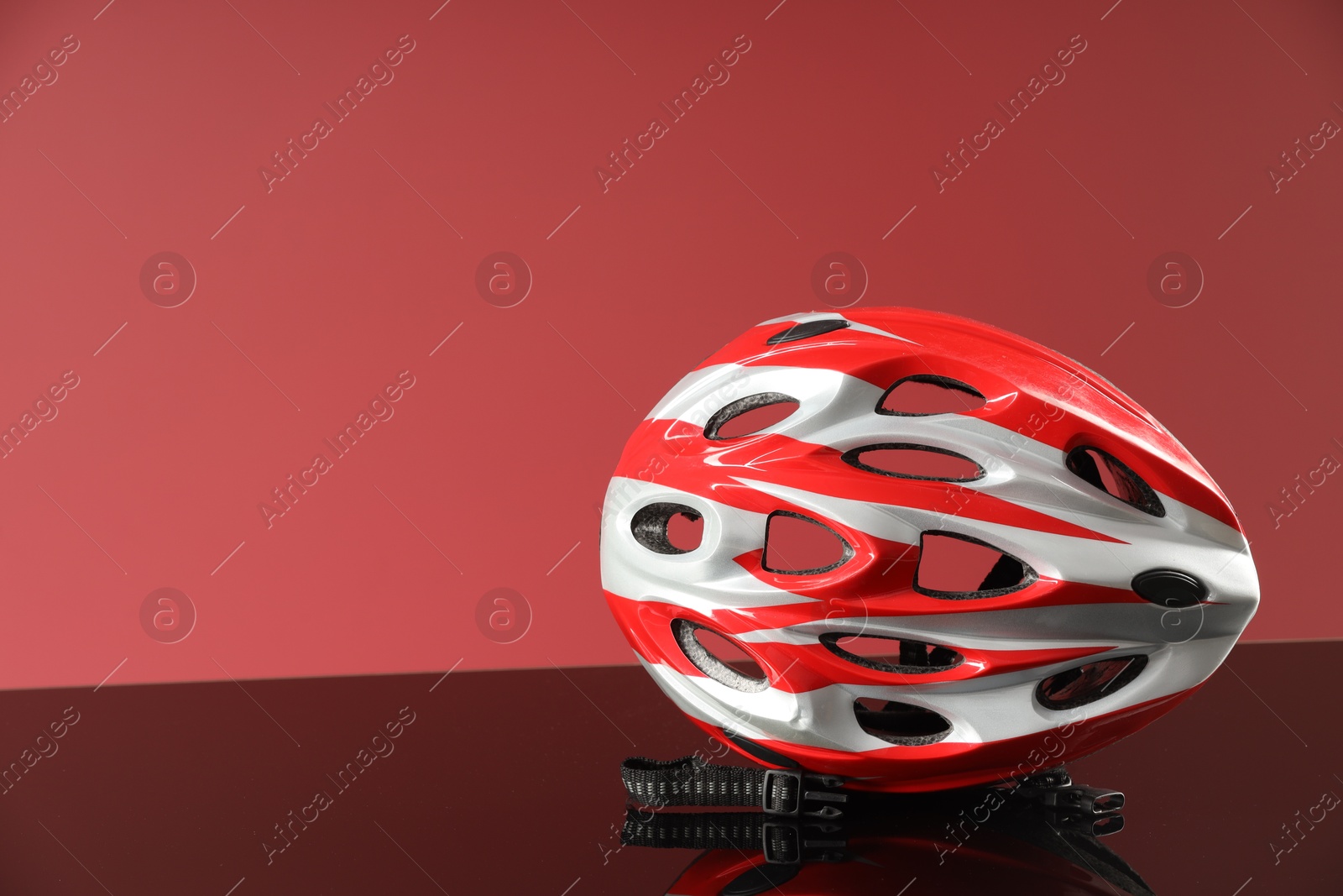 Photo of Protective helmet on mirror surface against pink background. Space for text