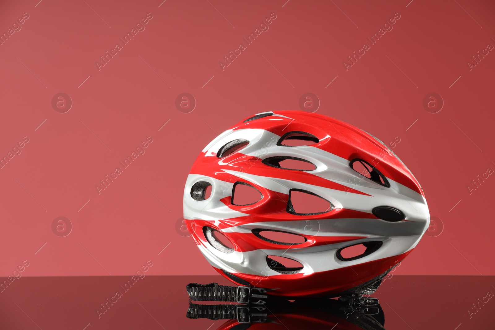 Photo of Protective helmet on mirror surface against pink background. Space for text