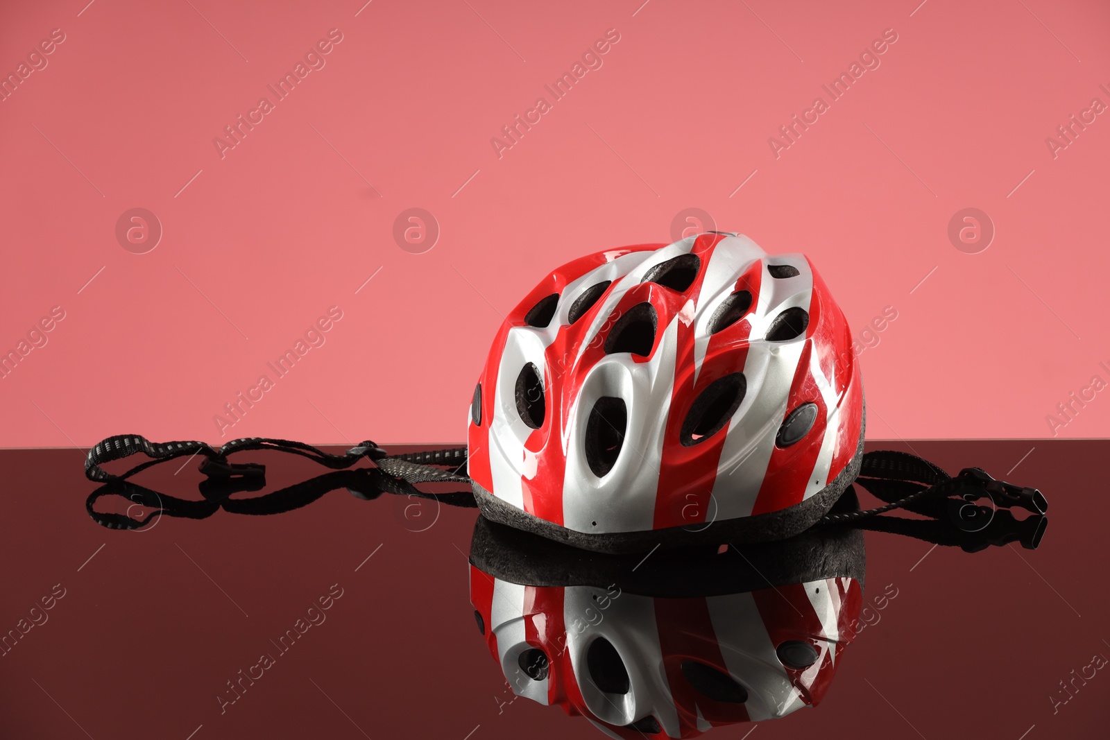 Photo of Protective helmet on mirror surface against pink background. Space for text