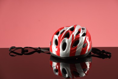 Protective helmet on mirror surface against pink background. Space for text