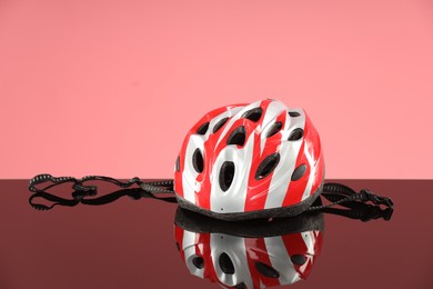 Photo of New protective helmet on mirror surface against pink background