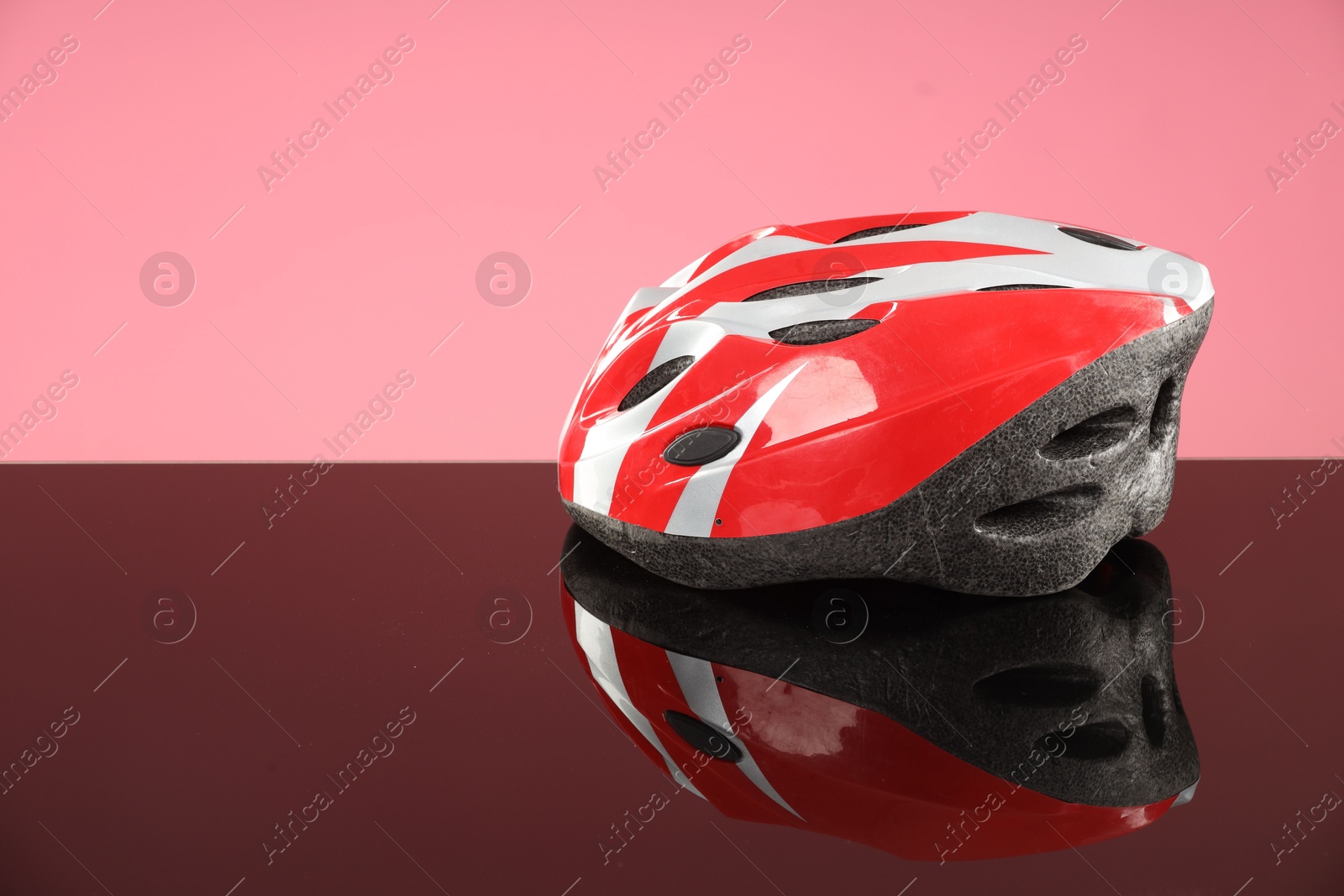 Photo of Protective helmet on mirror surface against pink background. Space for text