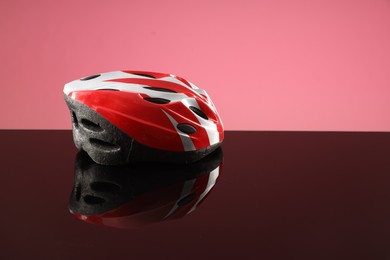 Protective helmet on mirror surface against pink background. Space for text