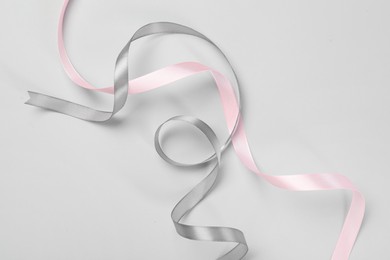 Photo of Beautiful grey and pink ribbons on white background, top view