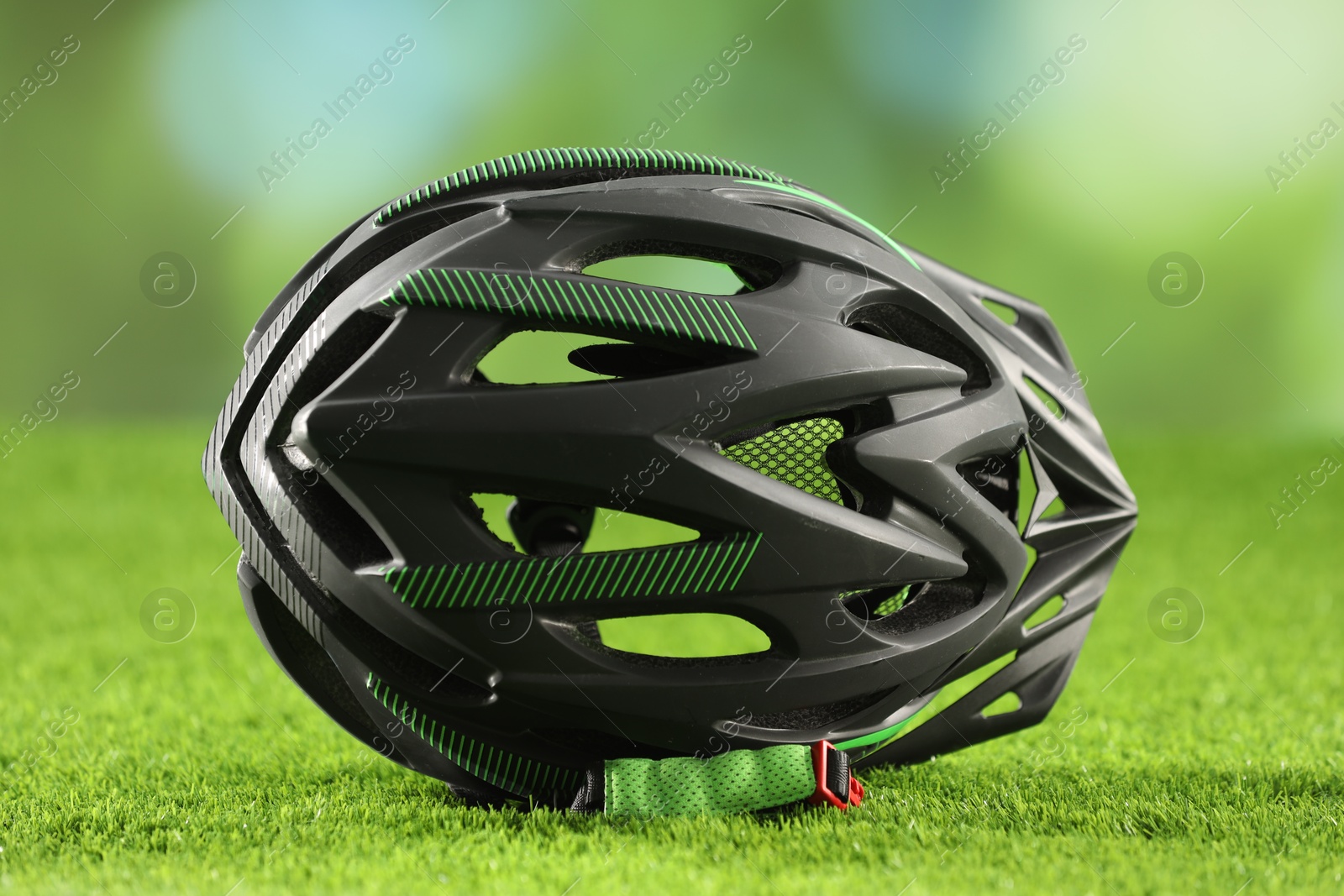 Photo of Stylish protective helmet on green grass against blurred background