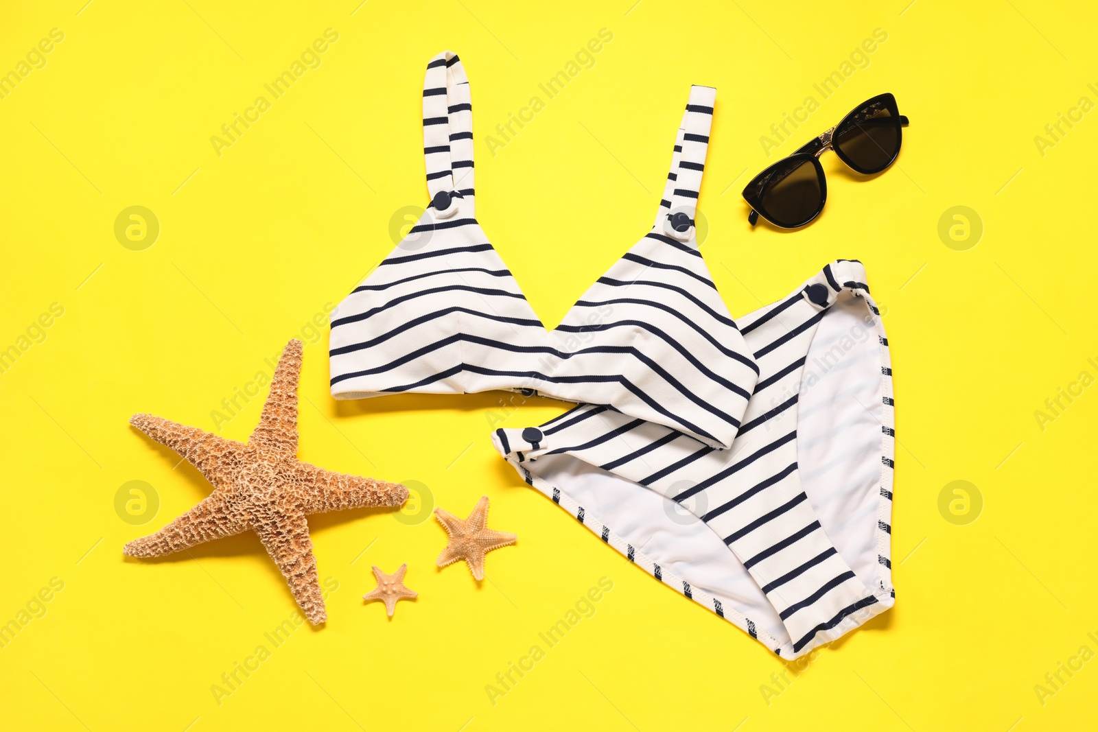 Photo of Flat lay composition with striped swimsuit and sunglasses on yellow background