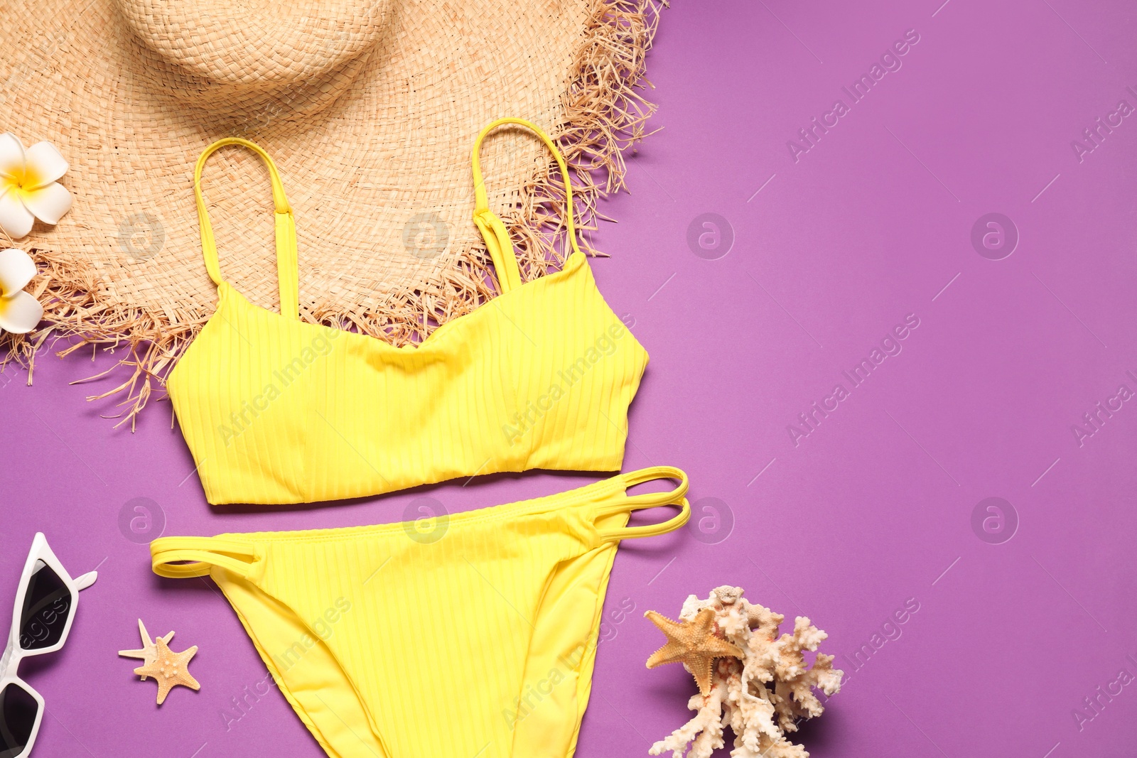 Photo of Flat lay composition with yellow swimsuit, hat and sunglasses on purple background. Space for text