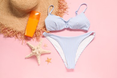 Striped swimsuit, sunscreen, hat and starfishes on pink background, flat lay