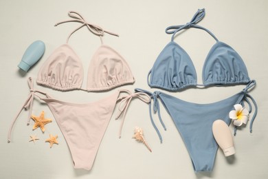 Photo of Beautiful swimsuits, sunscreens and starfishes on beige background, flat lay