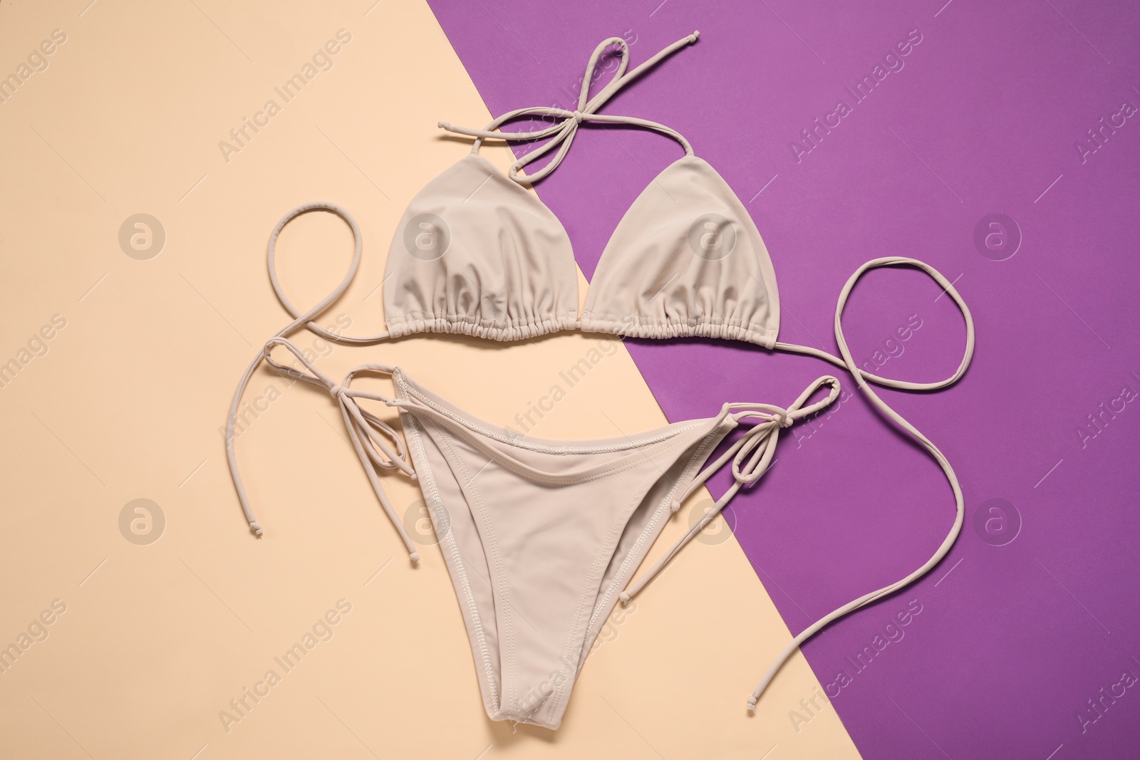 Photo of Beige swimsuit on color background, top view