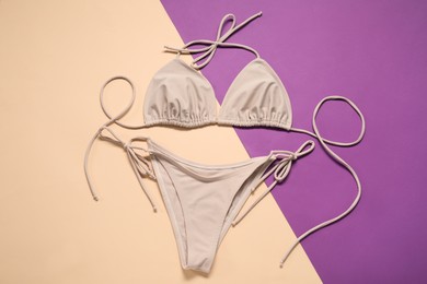 Photo of Beige swimsuit on color background, top view