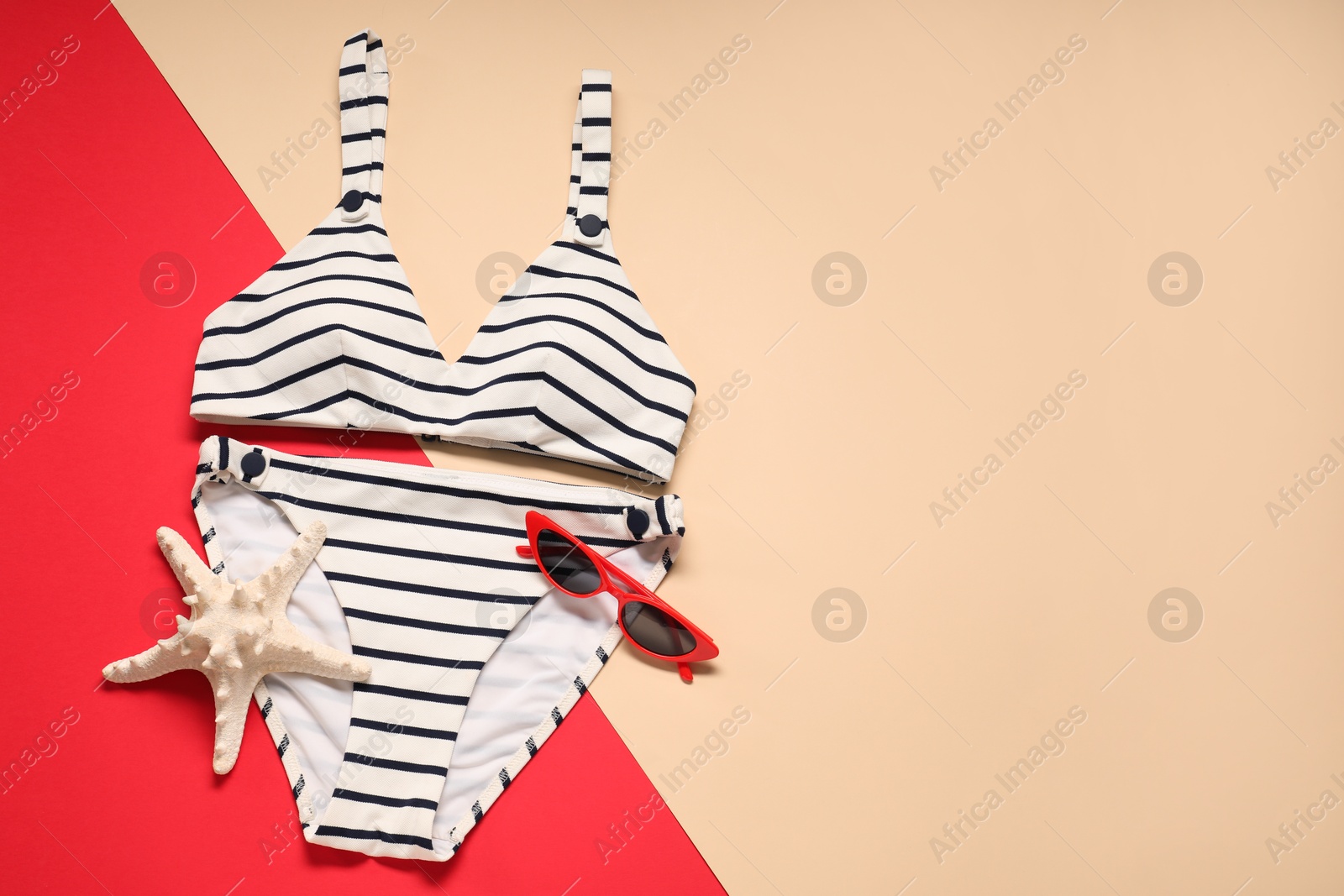 Photo of Striped swimsuit, sunglasses and starfish on color background, flat lay. Space for text