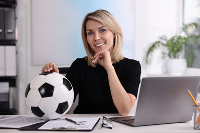 Photo of Smiling woman with soccer ball at table in office