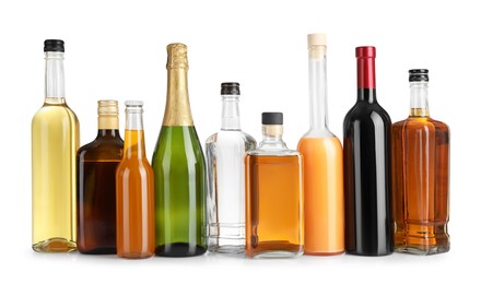 Bottles of different alcoholic drinks on white table against light background