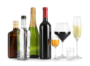 Bottles and glasses with different alcoholic drinks on white table against light background