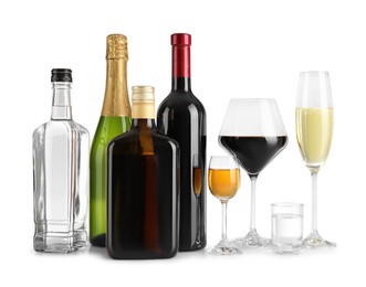 Photo of Bottles and glasses with different alcoholic drinks on white table against light background