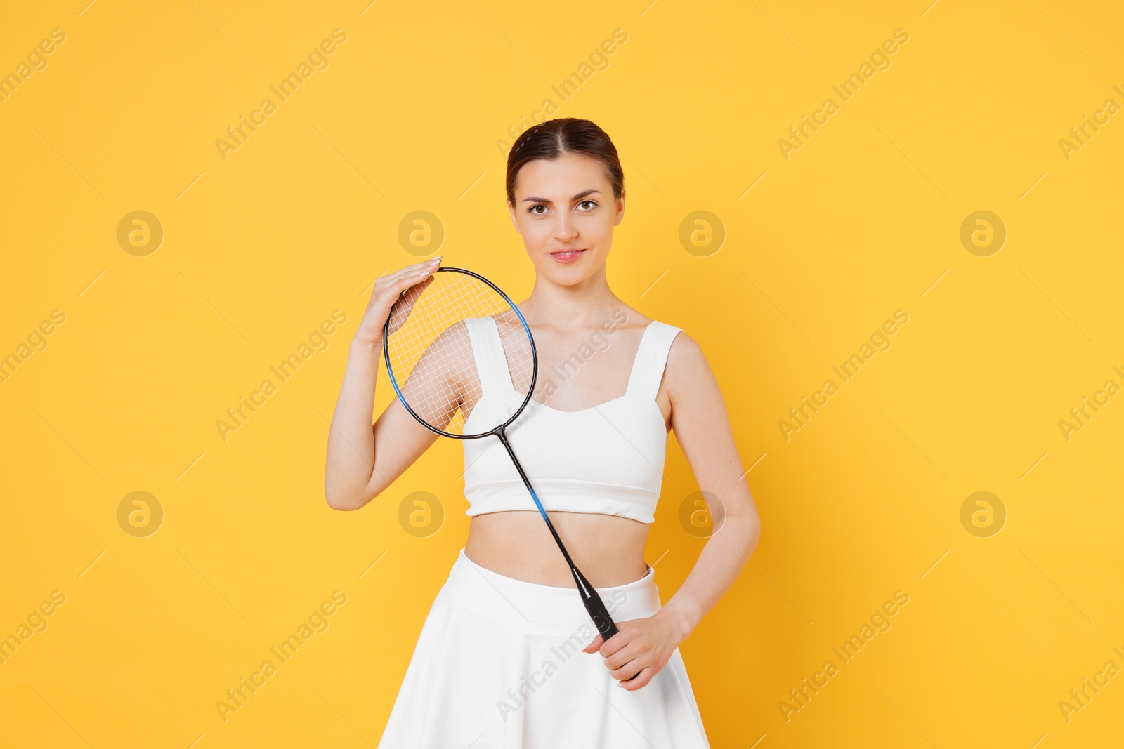 Photo of Young woman with badminton racket on orange background